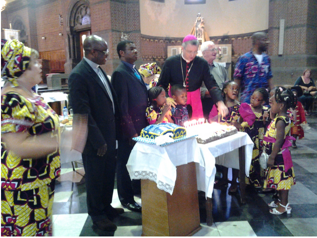 Mgr. Bonny snijdt de taart aan na de viering van de anglo-Afrikaanse gemeenschap
